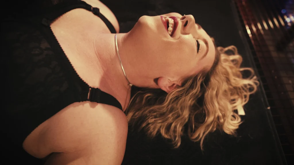 Beastie-FS lying back, laughing, with a silver collar and black lace lingerie